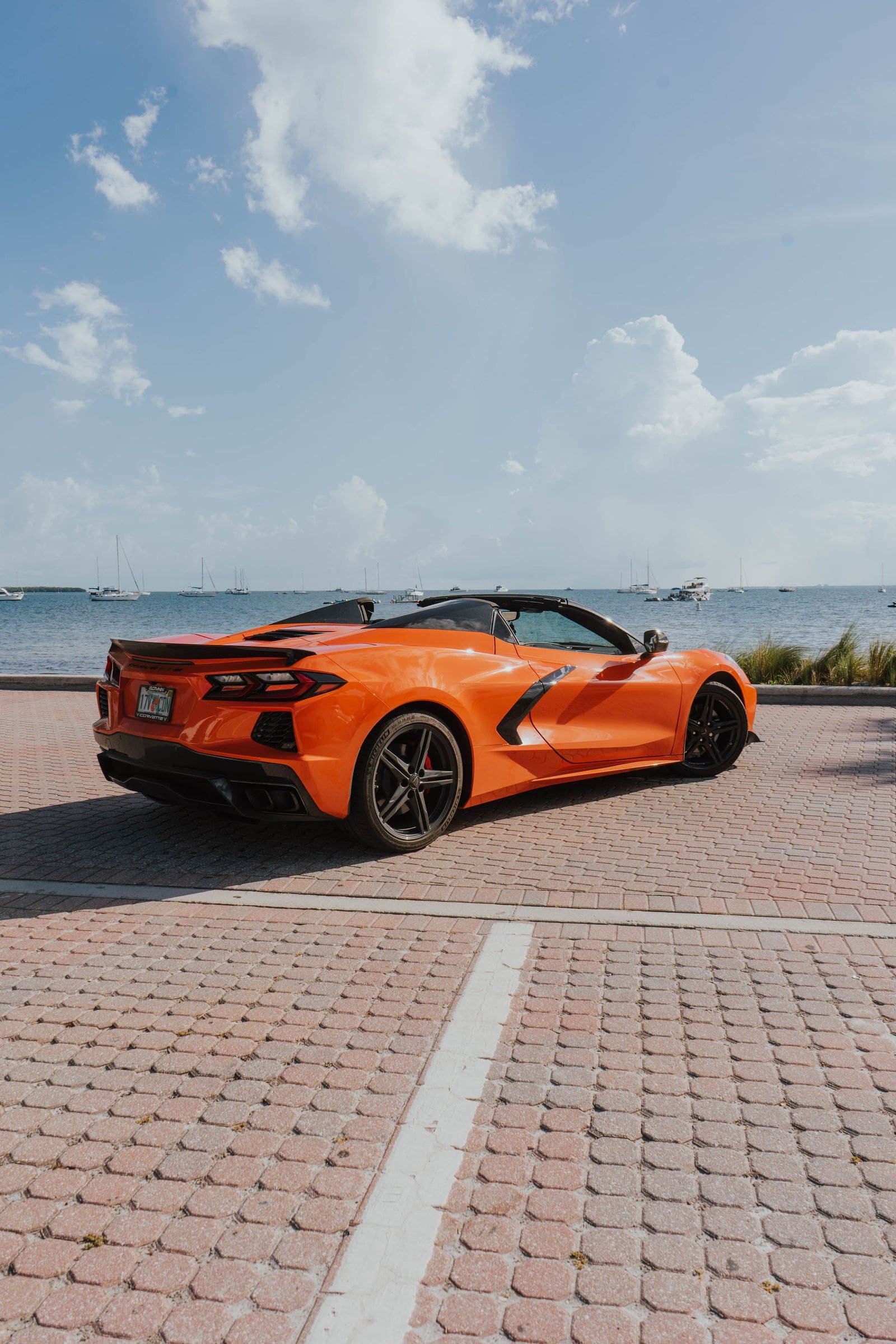 Rear three-quarter view of an orange Corvette C8 by the water